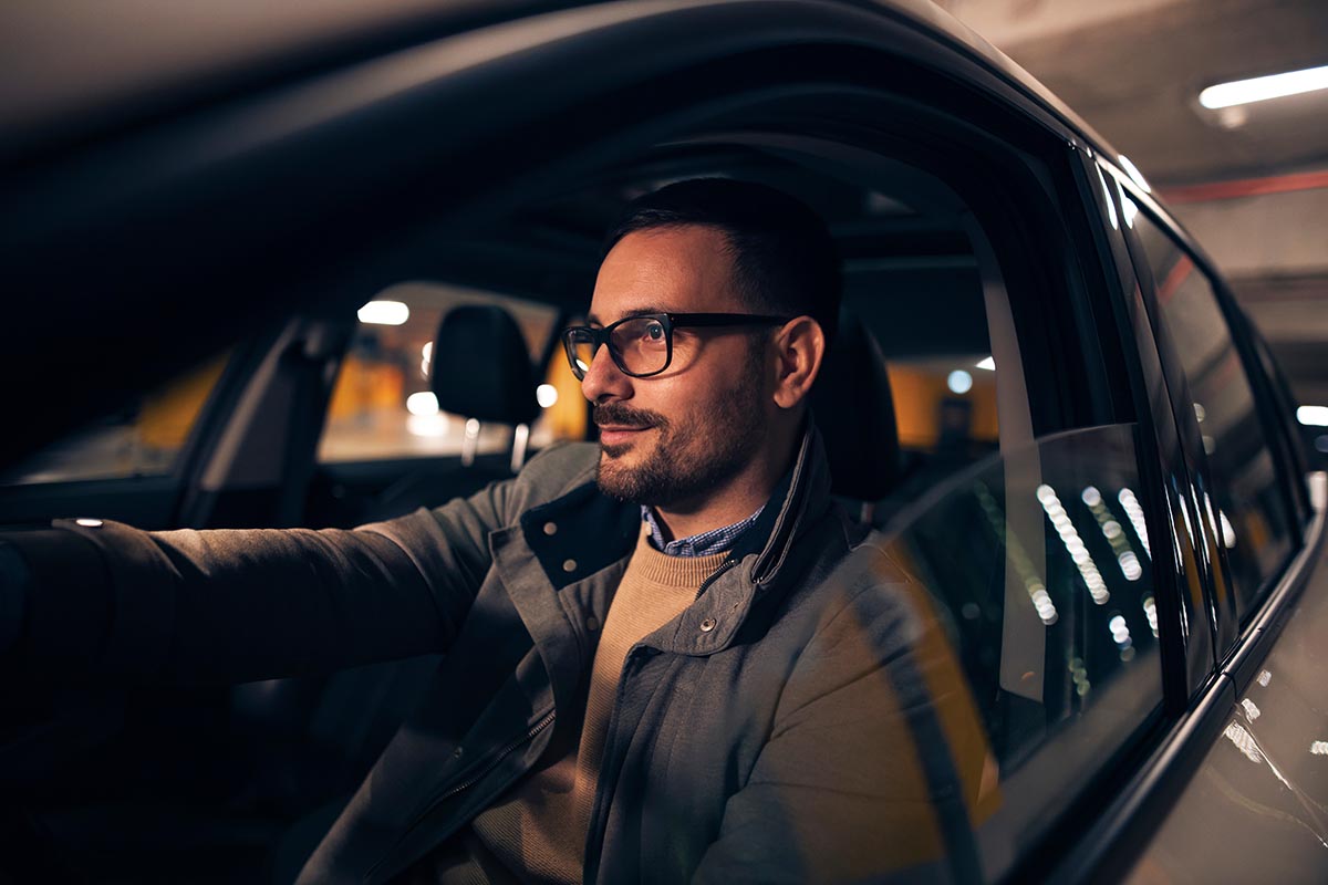 Side view portrait of a handsome stylish man driving car at night.